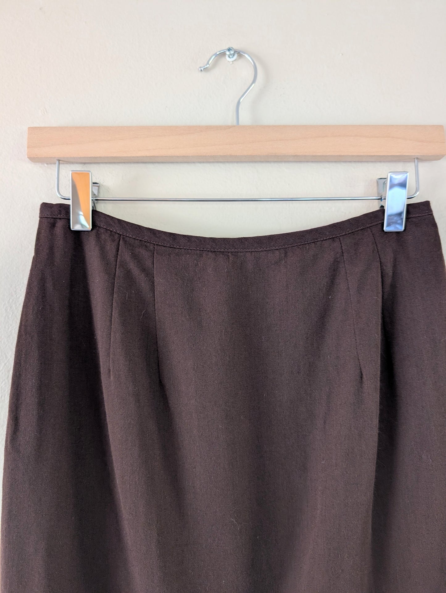 Brown skirt on a hanger against a plain background