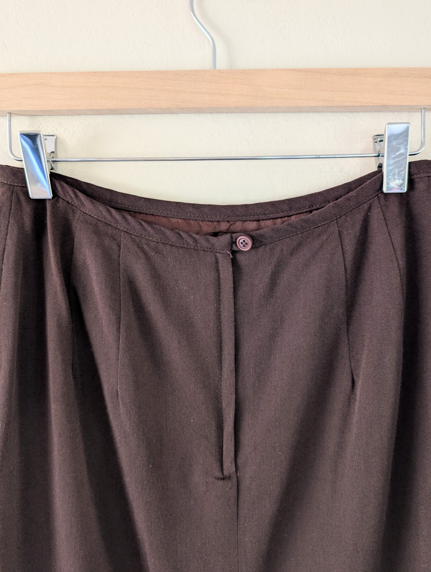 Brown pants hanging on a hanger against a white background