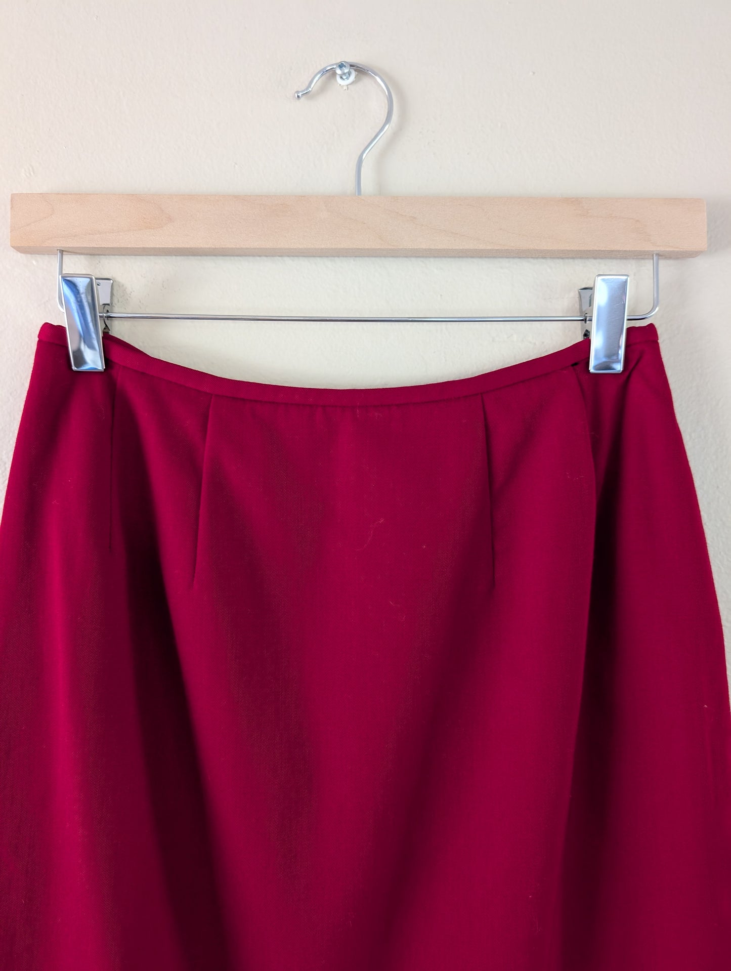 red wool pencil skirt on hanger against white background