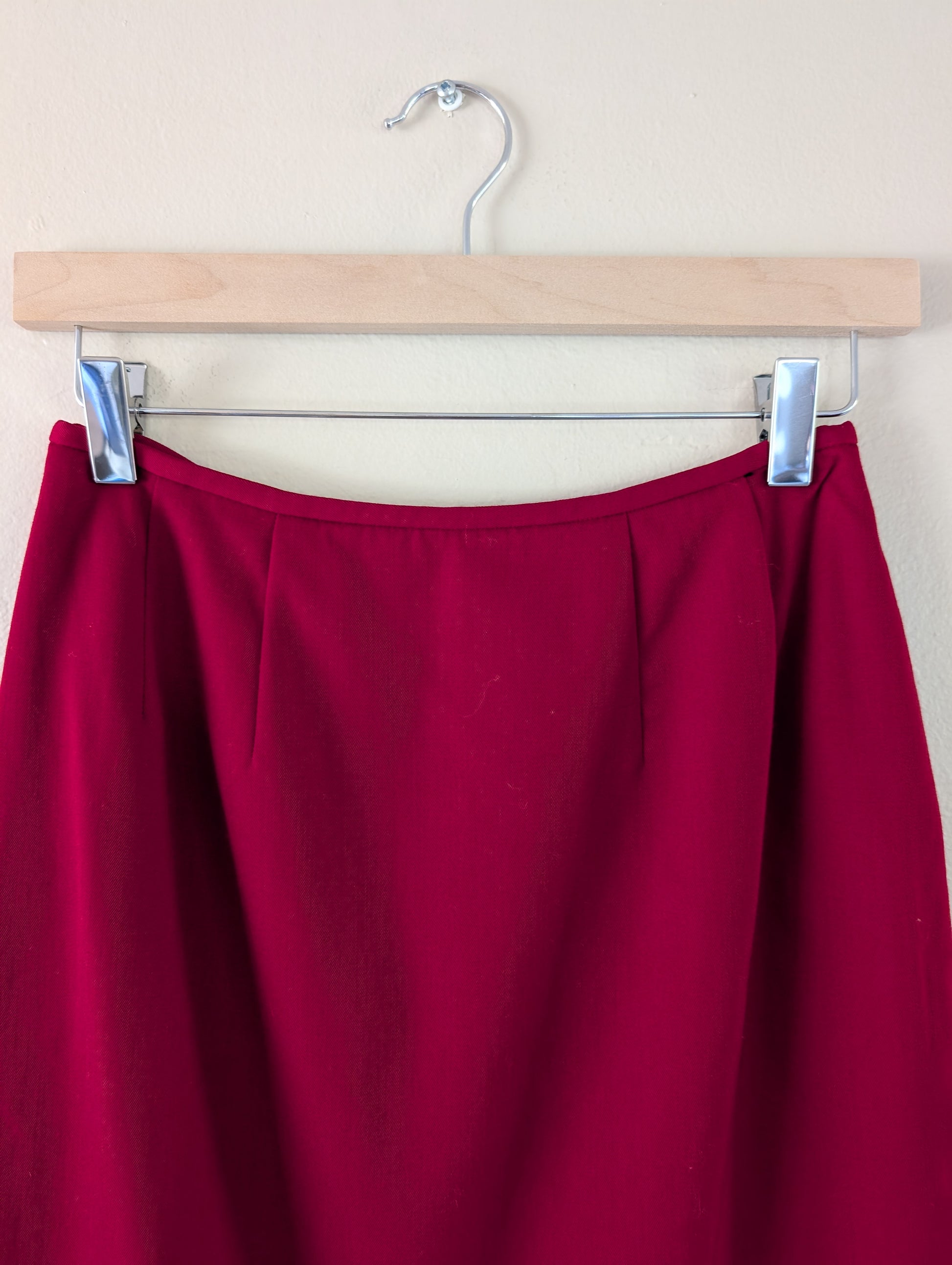 red wool pencil skirt on hanger against white background