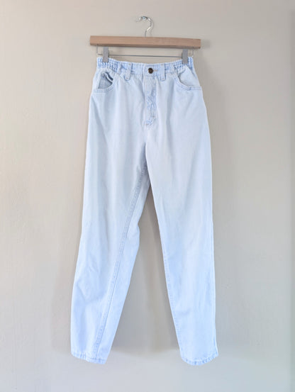 Light blue jeans on a hanger against a plain background