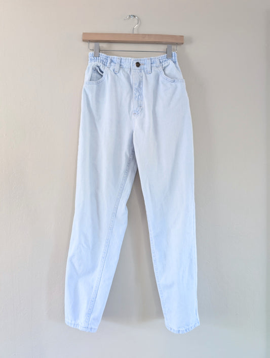 Light blue jeans on a hanger against a plain background