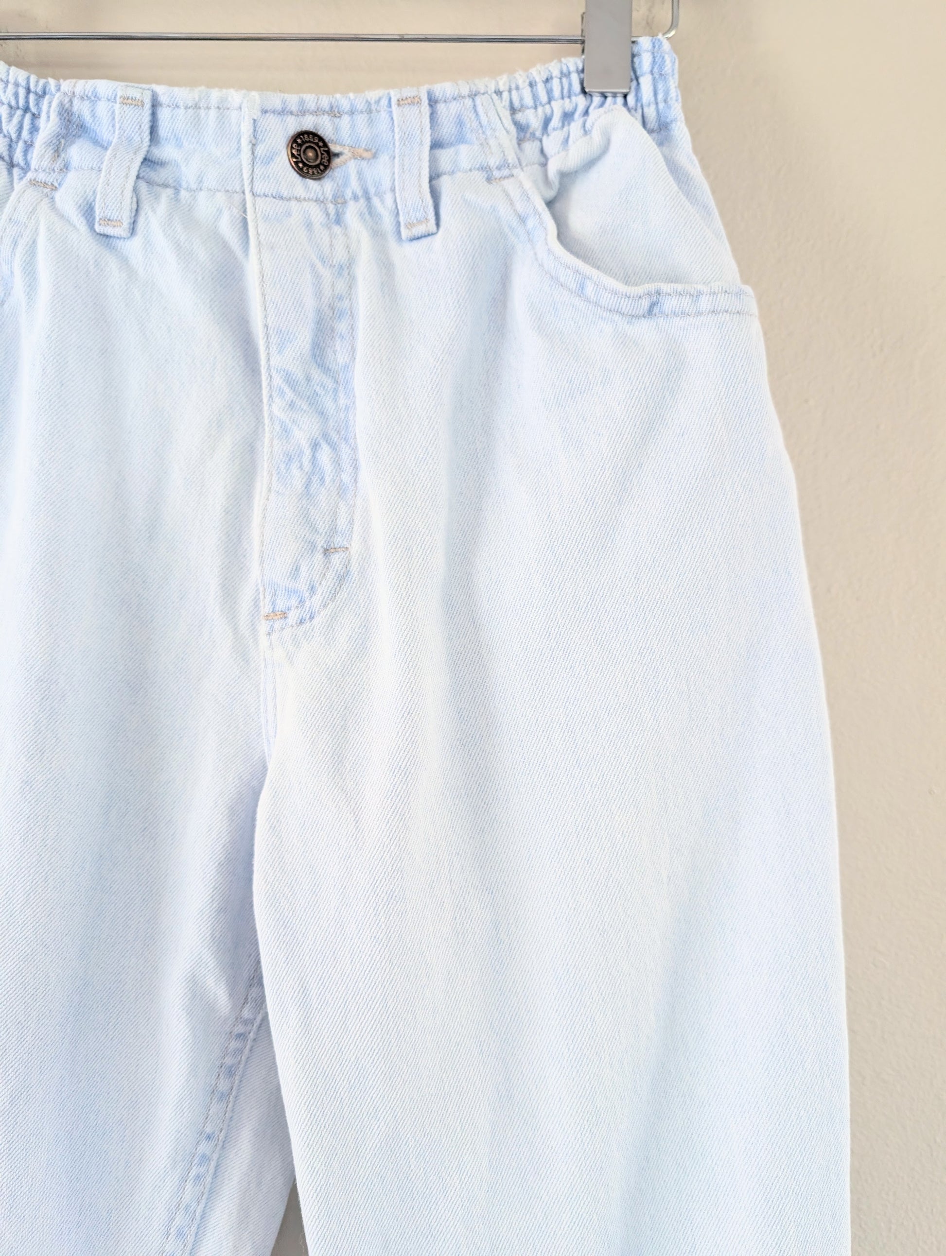 Light blue jeans with a button on a beige background