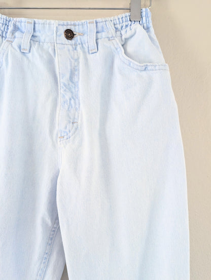 Light blue jeans with a button on a beige background