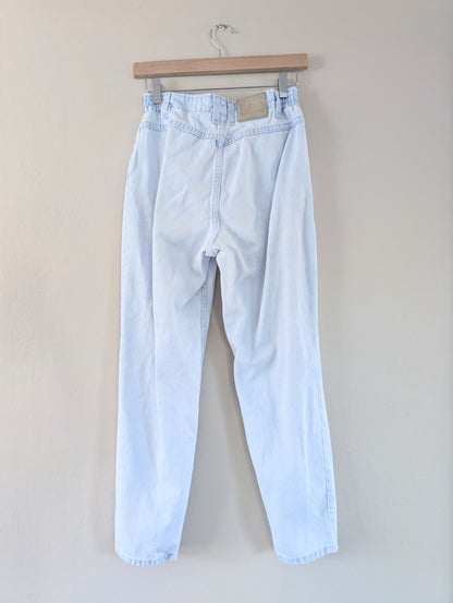 Light blue jeans hanging on a wooden hanger against a plain background