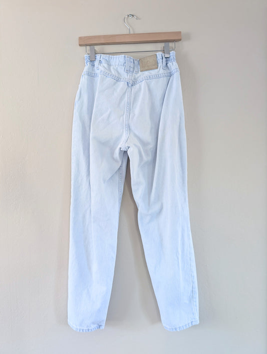 Light blue jeans hanging on a wooden hanger against a plain background