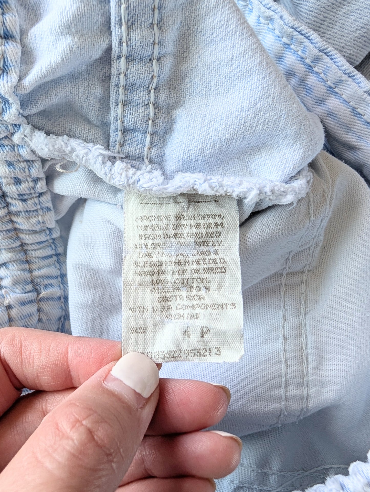 Close-up of a clothing tag on a piece of light blue fabric.