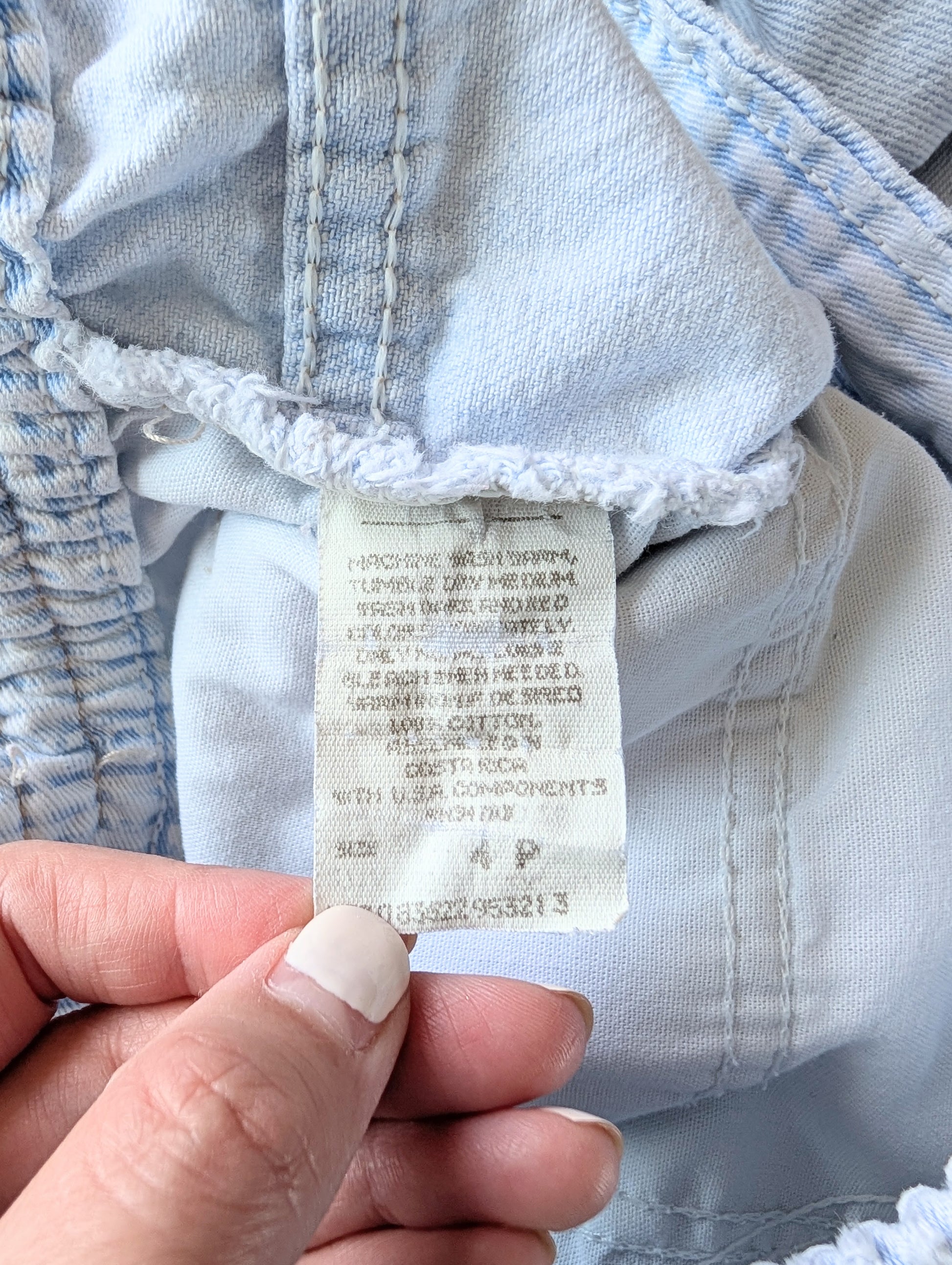 Close-up of a clothing tag on a piece of light blue fabric.